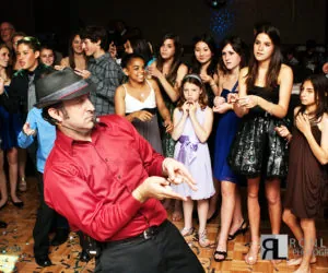 DJ Alvis in a red shirt dancing in the middle of a circle of teens.