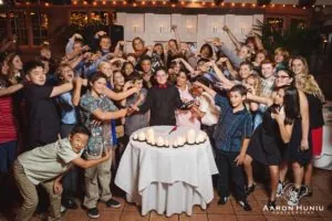 Kids crowding around a white cake for a group photo at El Adobe.