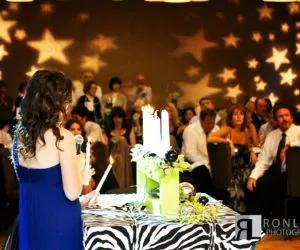 A candle-lighting ceremony at a cake under a ceiling of projected stars.