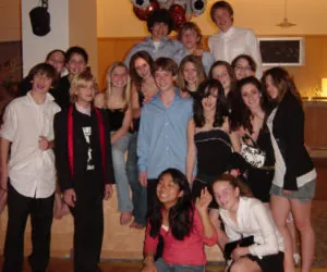A group of teens posing together in front of the DJ setup.