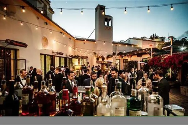 Guests mingling at cocktail hour on a Spanish-style patio under string lights.