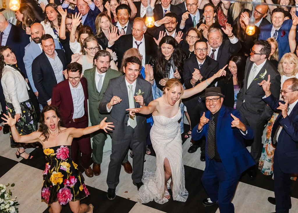 A packed dance floor of wedding guests cheering around the bride and groom at the Oviatt.