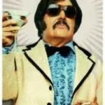 Tony Clifton in a white tuxedo jacket and dark glasses.