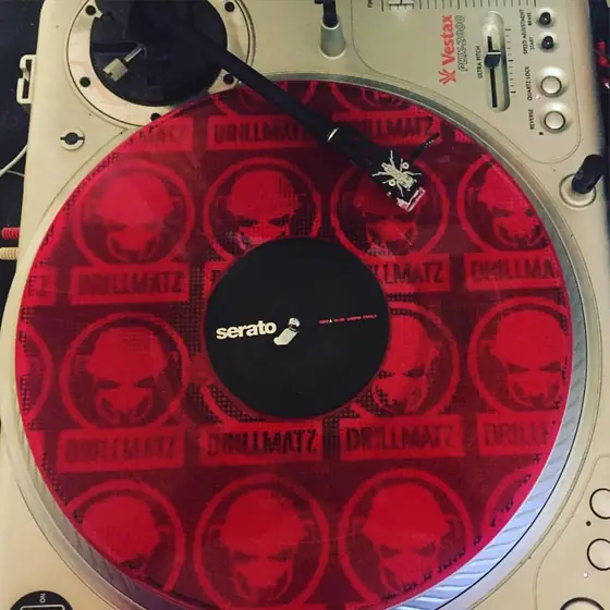 A red record spinning on a turntable, tonearm down.