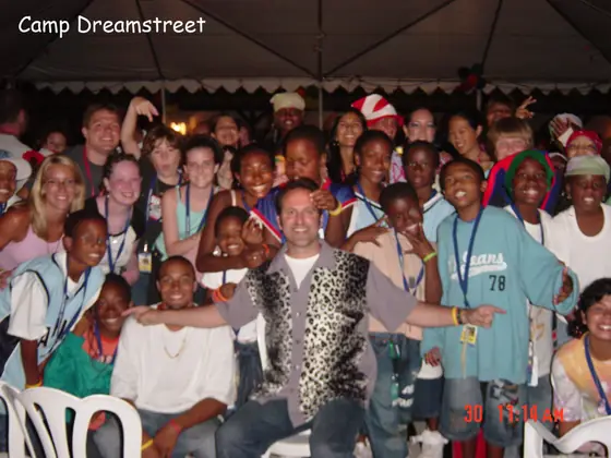 A big group of campers and counselors posing together under a tent.