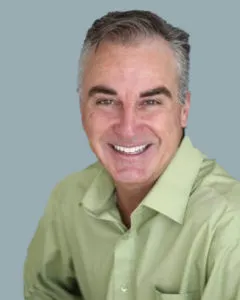 Dru Solari smiling in a green shirt.