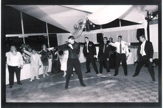 Black and white: the groom and his friends dancing in a line on a checkered floor.