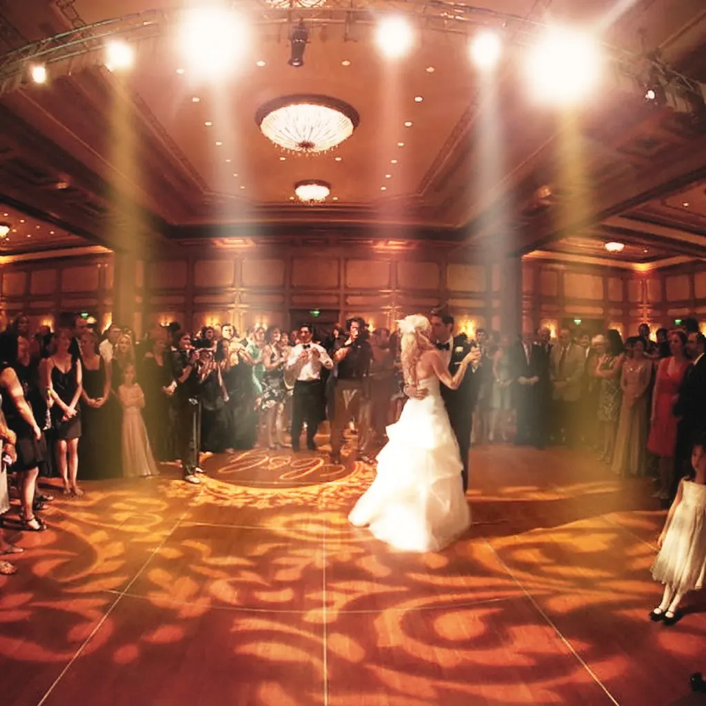 A ballroom washed in warm uplights during a first dance.