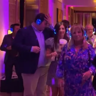 Party guests dancing in glowing wireless headphones.